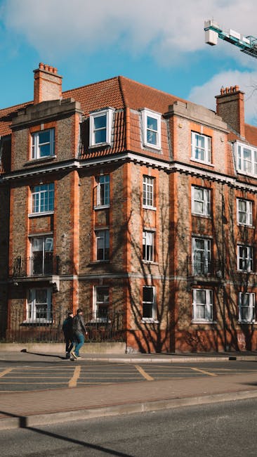 A tall, multi-storey residential building constructed from brown brick, with numerous small, rectangular windows aligned in vertical columns across its façade. The building extends upward into a clou